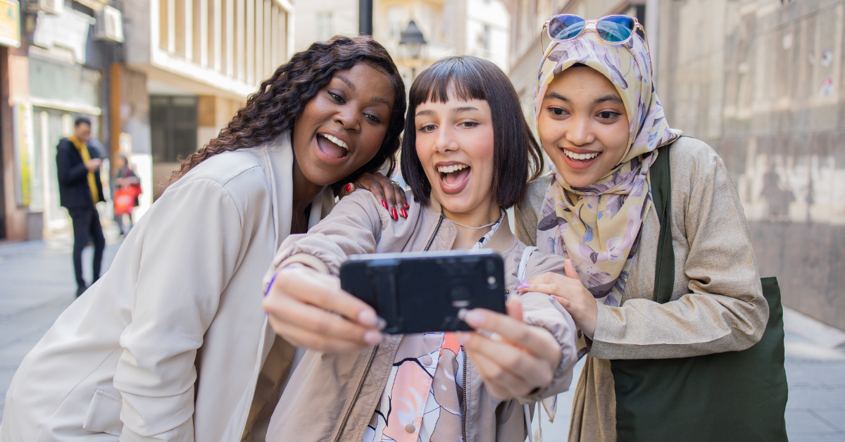 a group of 3 young adults (gen z) poses for a selfie